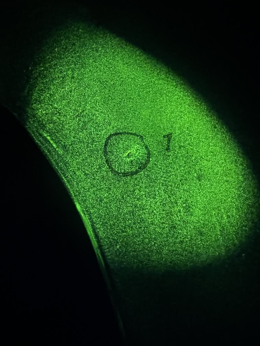 Fluorescerende indikasjon som lyser grønt under UV-lys, merket med nummer 1