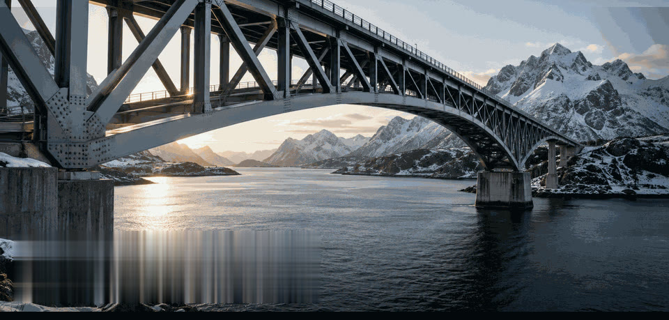 Stålbro i fagverk over fjord med snødekte fjell